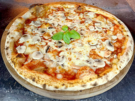Pizza mit frischen Champignons im Steinofen mit Holzfeuer gebacken